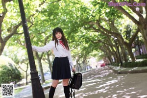 A woman in a white shirt holding a black purse.