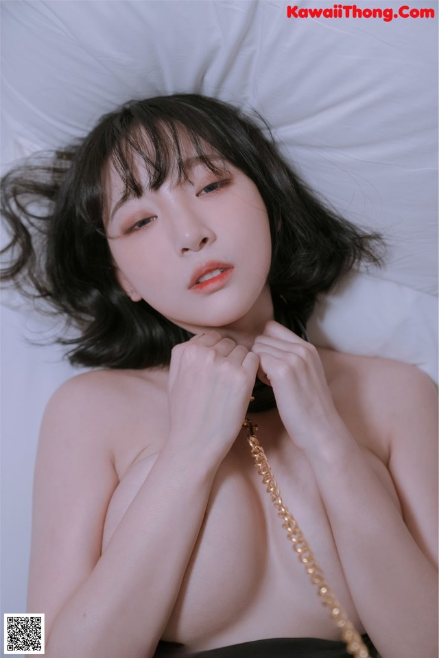 A woman laying on a bed with a necklace around her neck.