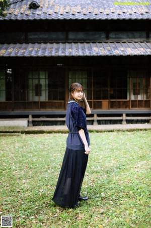 A young woman in a blue jacket standing in the woods.