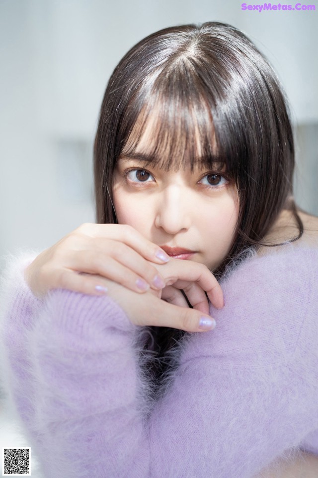 A woman in a purple sweater is posing for a picture.