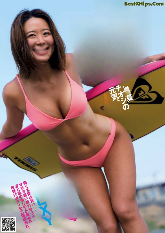 A woman in a pink bikini holding a surfboard.