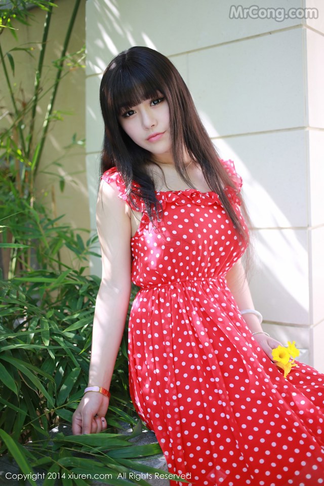 A woman in a red polka dot dress posing for a picture.