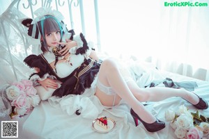 A woman in a maid outfit holding a piece of cake.