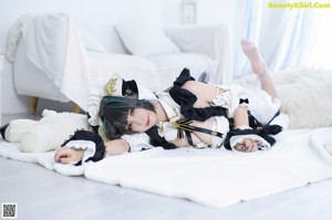 A woman in a maid outfit sitting on the floor.