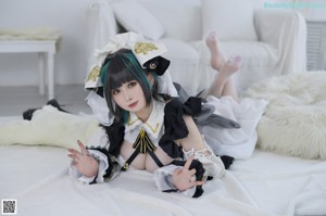 A woman laying on top of a bed in a maid outfit.