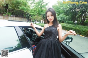 A woman in a white dress sitting on top of a white car.