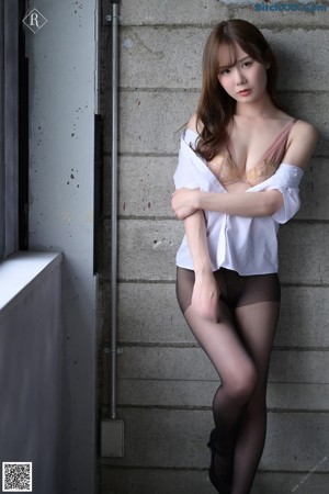 A woman in a white shirt and black stockings sitting on a bench.