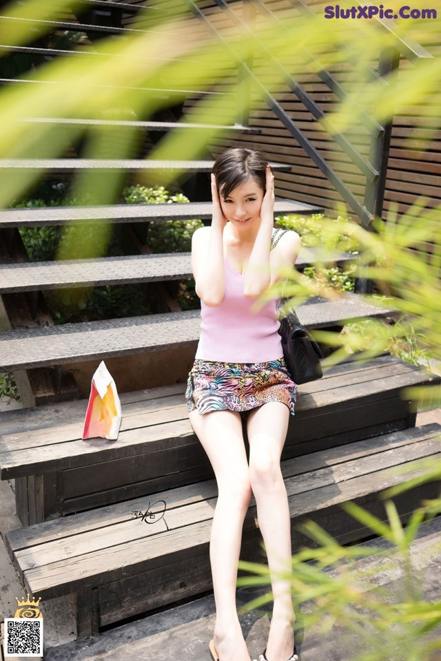 A woman sitting on a set of stairs talking on a cell phone.