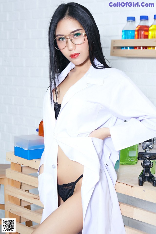 A woman in a lab coat and glasses posing for a picture.