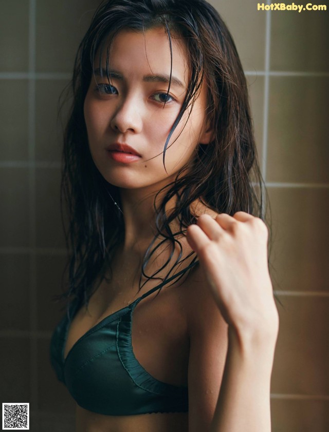 A woman in a green bikini standing in a bathroom.