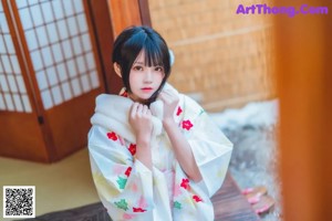 A woman in a kimono sitting on a wooden table.