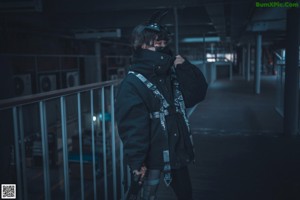 A woman standing in a long hallway holding a gun.