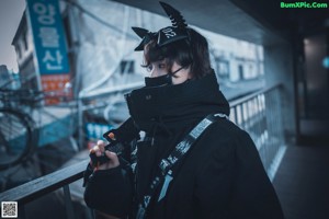 A person wearing a mask and goggles standing in front of a railing.