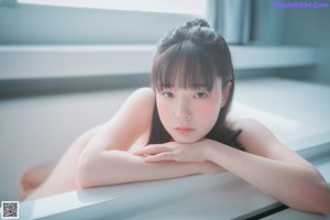 A doll sitting in a bathtub with water on her legs.
