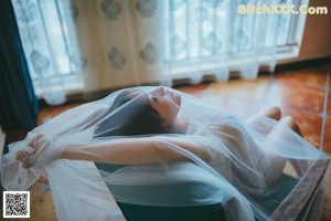 A woman in a white lingerie crouching on a tiled floor.