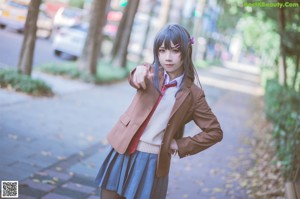 A woman in a school uniform holding a cell phone.