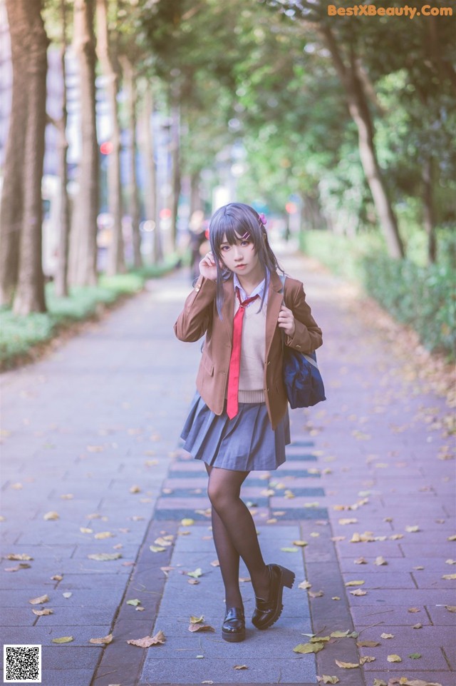 A woman in a school uniform is walking down a sidewalk.