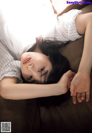 A woman laying on top of a bed next to a pillow.