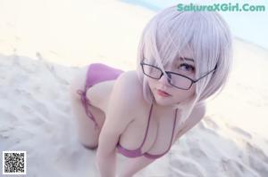 A woman in a pink bikini and glasses on the beach.