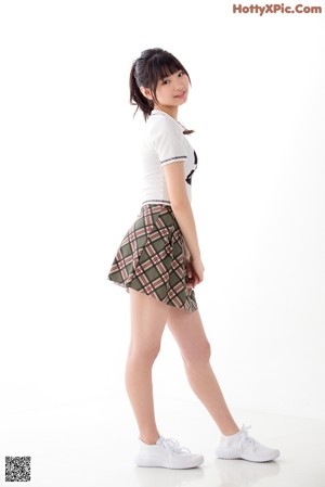 A woman in a white shirt and plaid skirt posing for a picture.