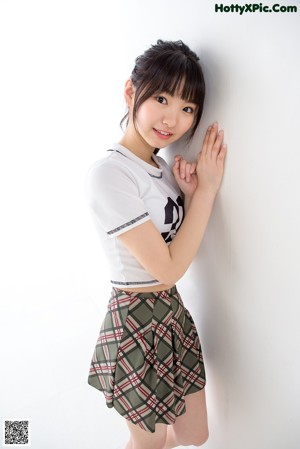 A woman in a white shirt and plaid skirt posing for a picture.