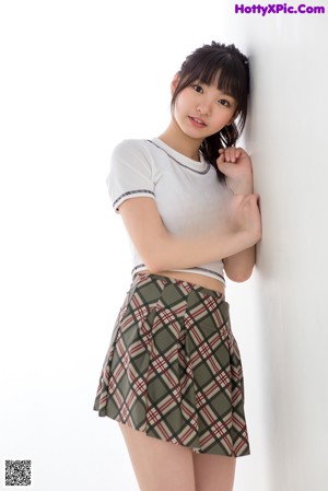A woman in a white shirt and plaid skirt posing for a picture.
