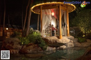 A woman standing in front of a gazebo in the middle of a pond.