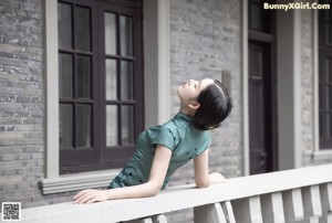 A woman in a green dress is walking up some stairs.