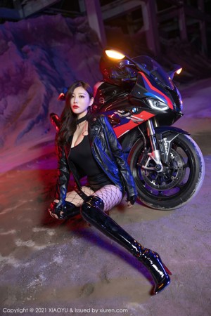 A woman sitting on a motorcycle in a dark room.