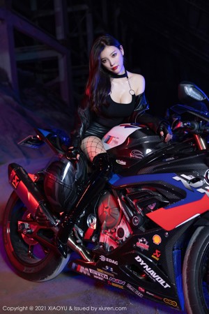 A woman in a black bodysuit sitting on a motorcycle.