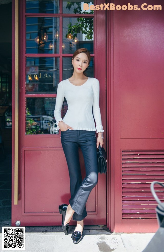 A woman standing in front of a red door.