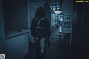 A woman in a black outfit holding a chainsaw.