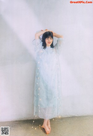 A woman in a white dress sitting on a chair.