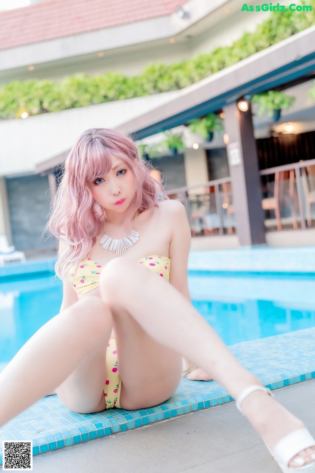 A woman in a bikini sitting by a swimming pool.