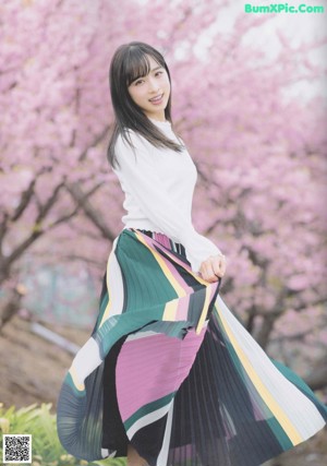 A woman standing in front of a flowering tree.