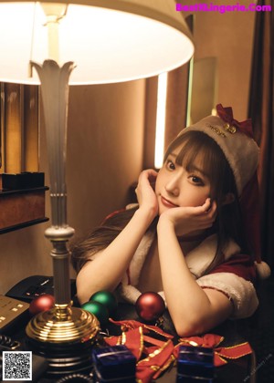 A woman in a santa claus outfit decorating a Christmas tree.