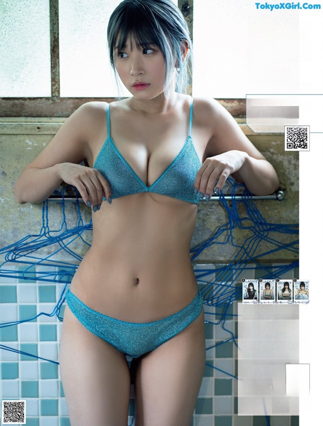 A woman in a blue bikini standing in a bathroom.