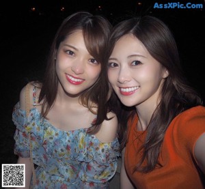 A couple of women standing next to each other eating ice cream.